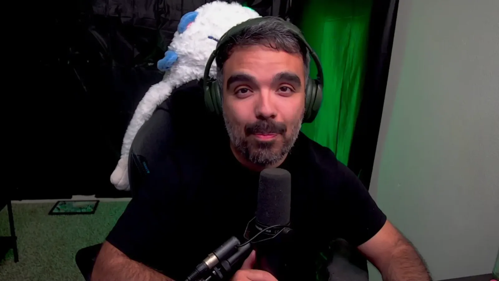 AniimoSync on camera after the Aniimo Season 1 Part 2 trailer, in headphones at his microphone with a white Aniimo plush behind him